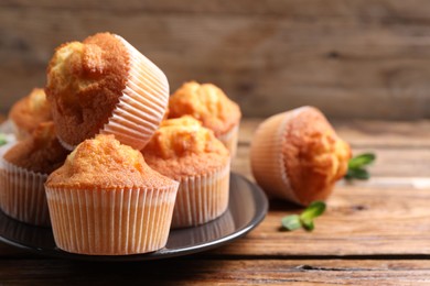 Photo of Delicious sweet muffins on wooden table, closeup. Space for text