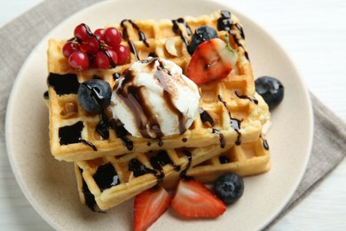 Photo of Delicious Belgian waffles with ice cream, berries and chocolate sauce on white wooden table, above view