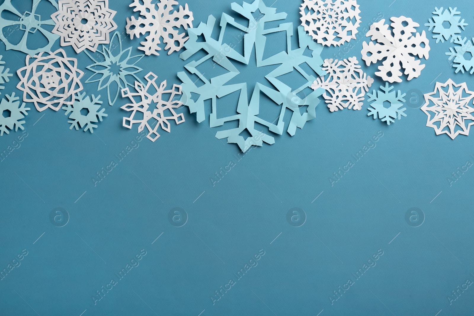 Photo of Many paper snowflakes on turquoise background, flat lay. Space for text