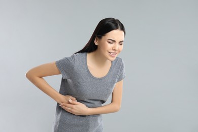 Woman suffering from liver pain on grey background