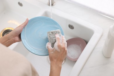 Photo of Woman washing plate in modern kitchen, above view