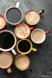 Many cups of different coffees on slate table, flat lay