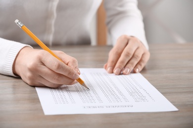 Photo of Student filling answer sheet at table, closeup