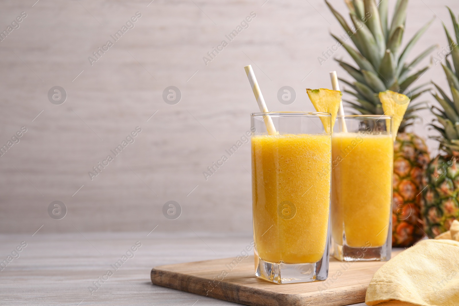 Photo of Tasty pineapple smoothie on wooden table, space for text