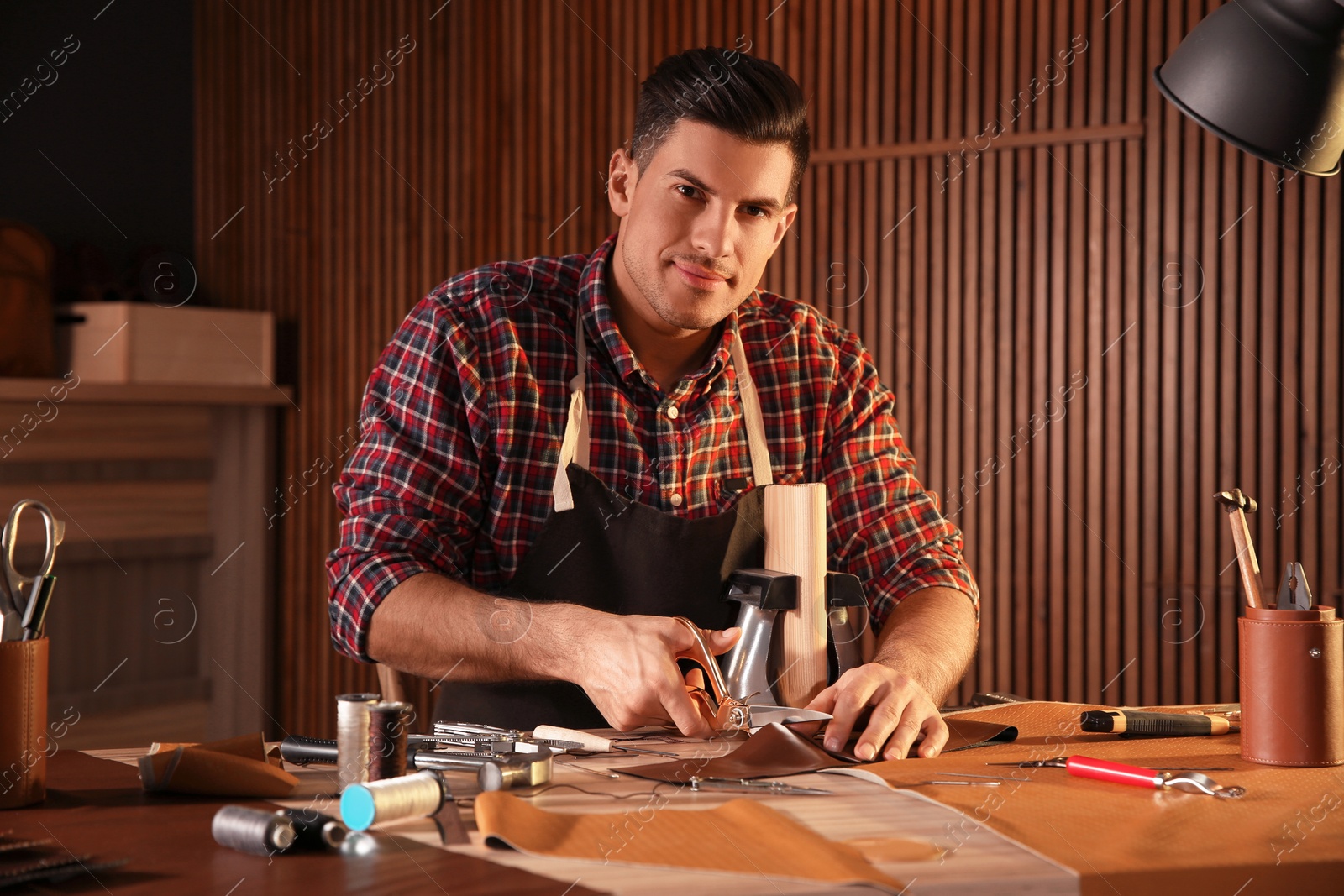 Photo of Man cutting leather with scissors in workshop