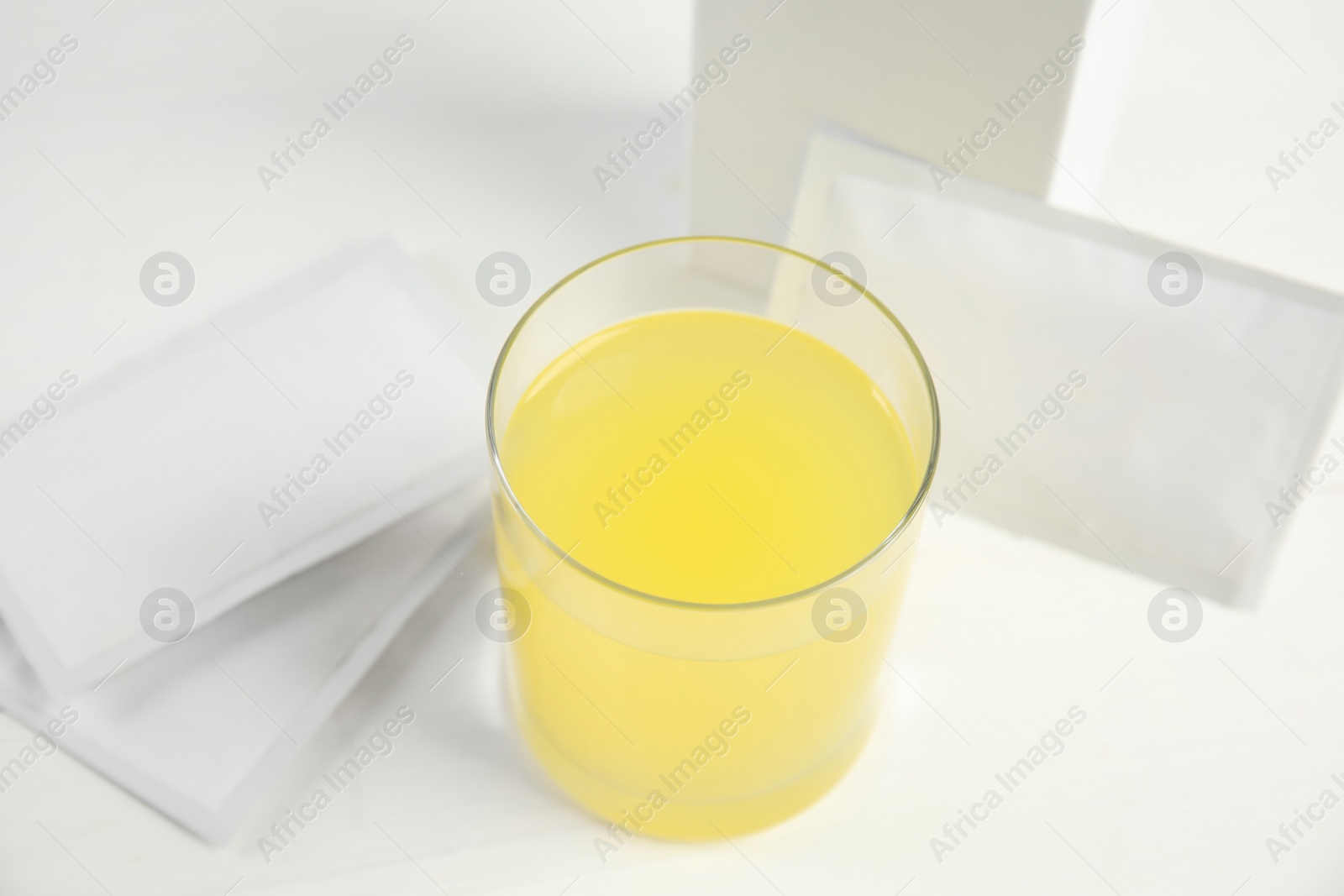 Photo of Medicine sachets and glass with dissolved drug on white table