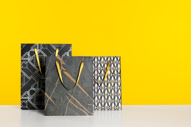 Photo of Stylish shopping paper bags on yellow background. Space for text