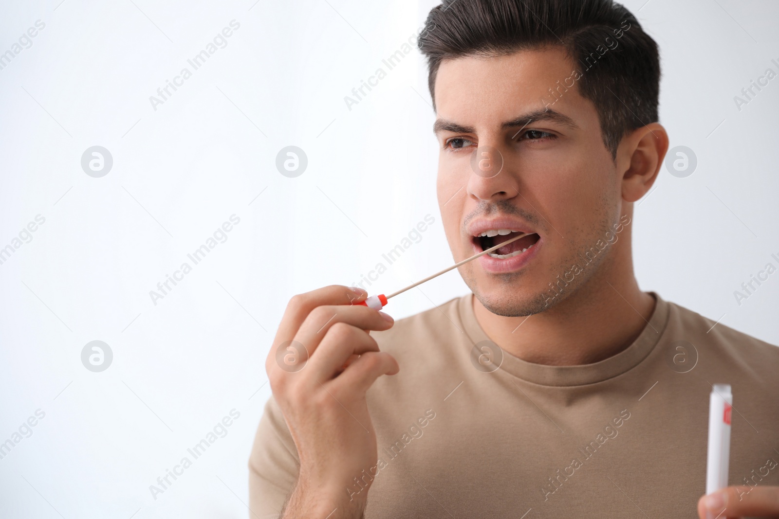 Photo of Man taking sample for DNA test on light background