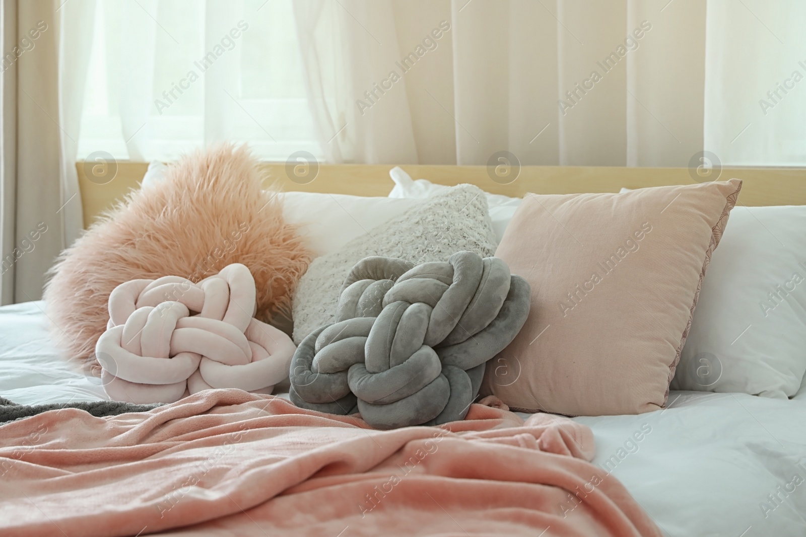 Photo of Cozy bed with different pillows and plaid in light room. Idea for interior decor