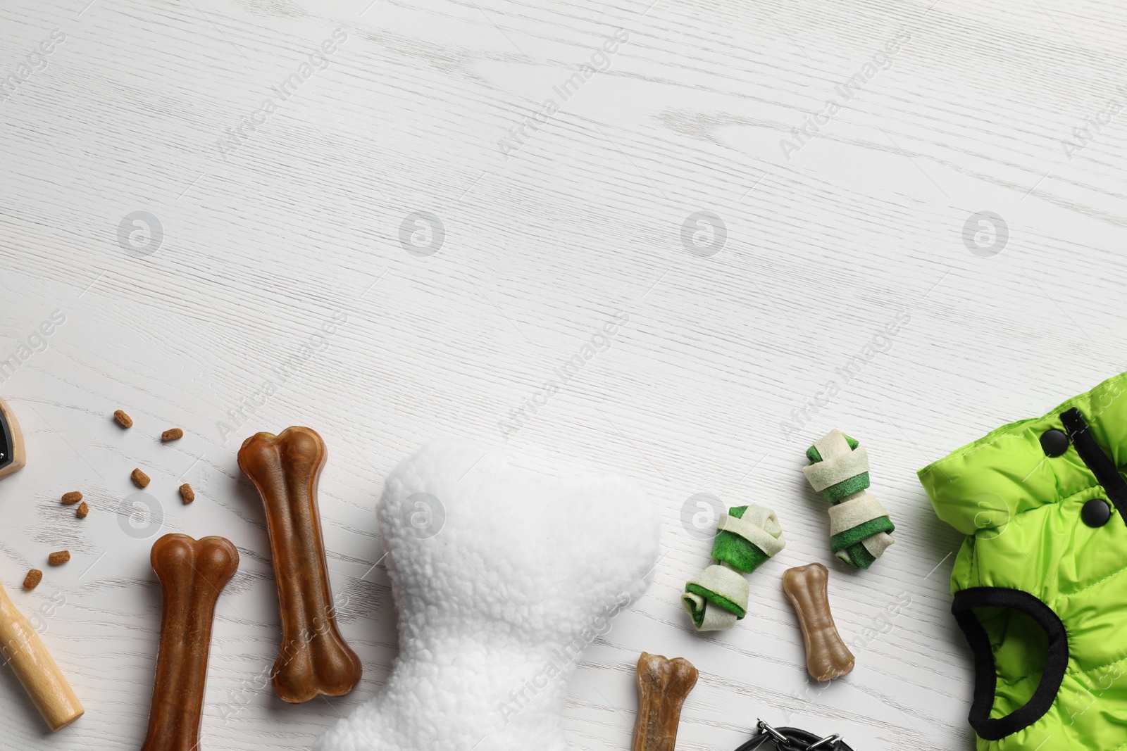 Photo of Flat lay composition with dog clothes, food and accessories on white wooden table. Space for text