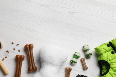 Flat lay composition with dog clothes, food and accessories on white wooden table. Space for text