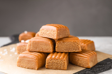 Photo of Delicious salted caramel on parchment, closeup view