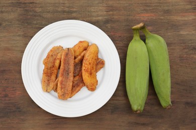 Photo of Delicious fried bananas and fresh fruits on wooden table, flat lay