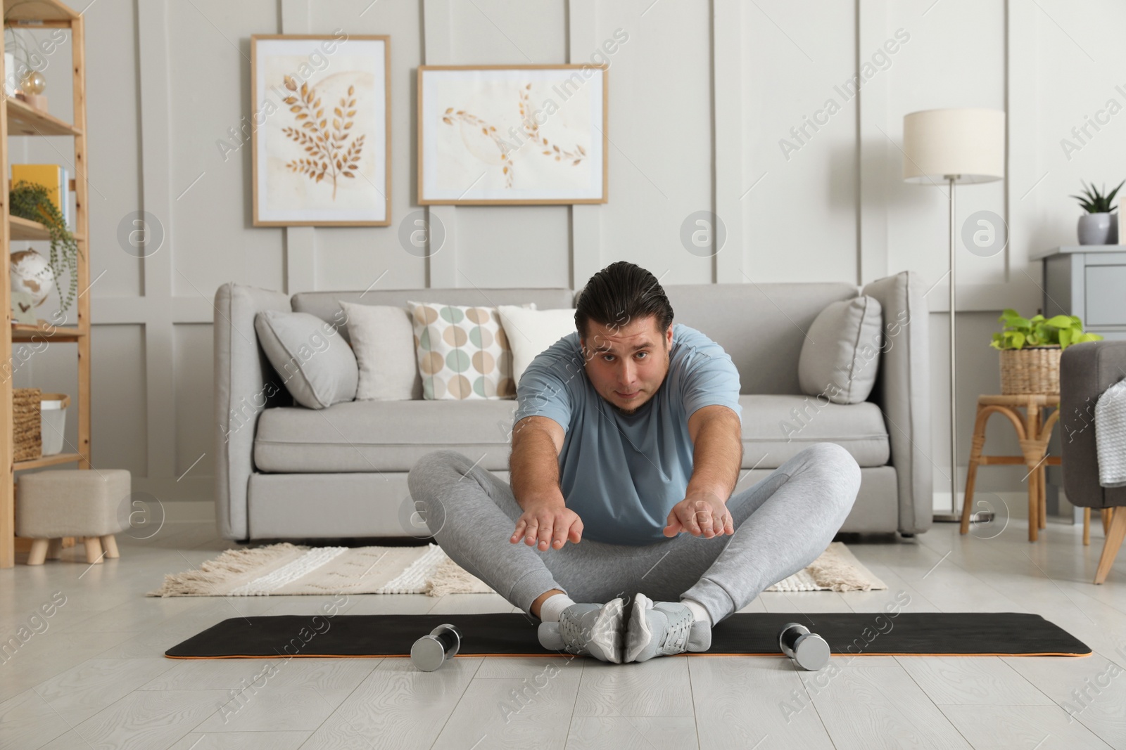 Photo of Overweight man stretching on mat at home