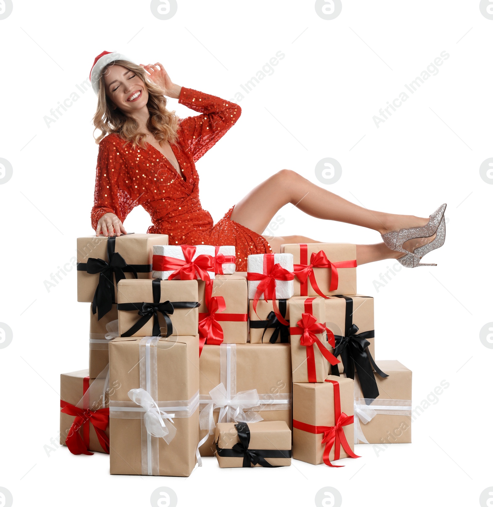 Photo of Beautiful young woman in Santa hat with pile of Christmas presents on white background