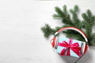 Flat lay composition with gift box and headphones on wooden background. Christmas music concept