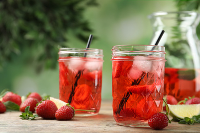 Photo of Refreshing drink with strawberry and lime on wooden table