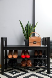 Photo of Shelving unit with stylish shoes and bag near grey wall in hallway