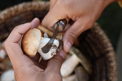 Photo of Man peeling mushroom with knife over basket, closeup