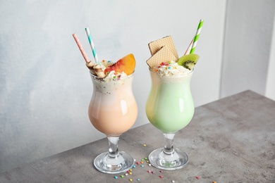 Glasses with delicious milk shakes on table against light background