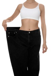 Young woman wearing big jeans after weight loss on white background, closeup