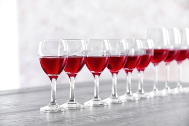 Photo of Glasses with delicious red wine on table