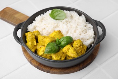 Photo of Delicious rice and chicken with curry sauce on white tiled table, closeup