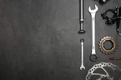 Set of different bicycle tools and parts on grey stone table, flat lay. Space for text