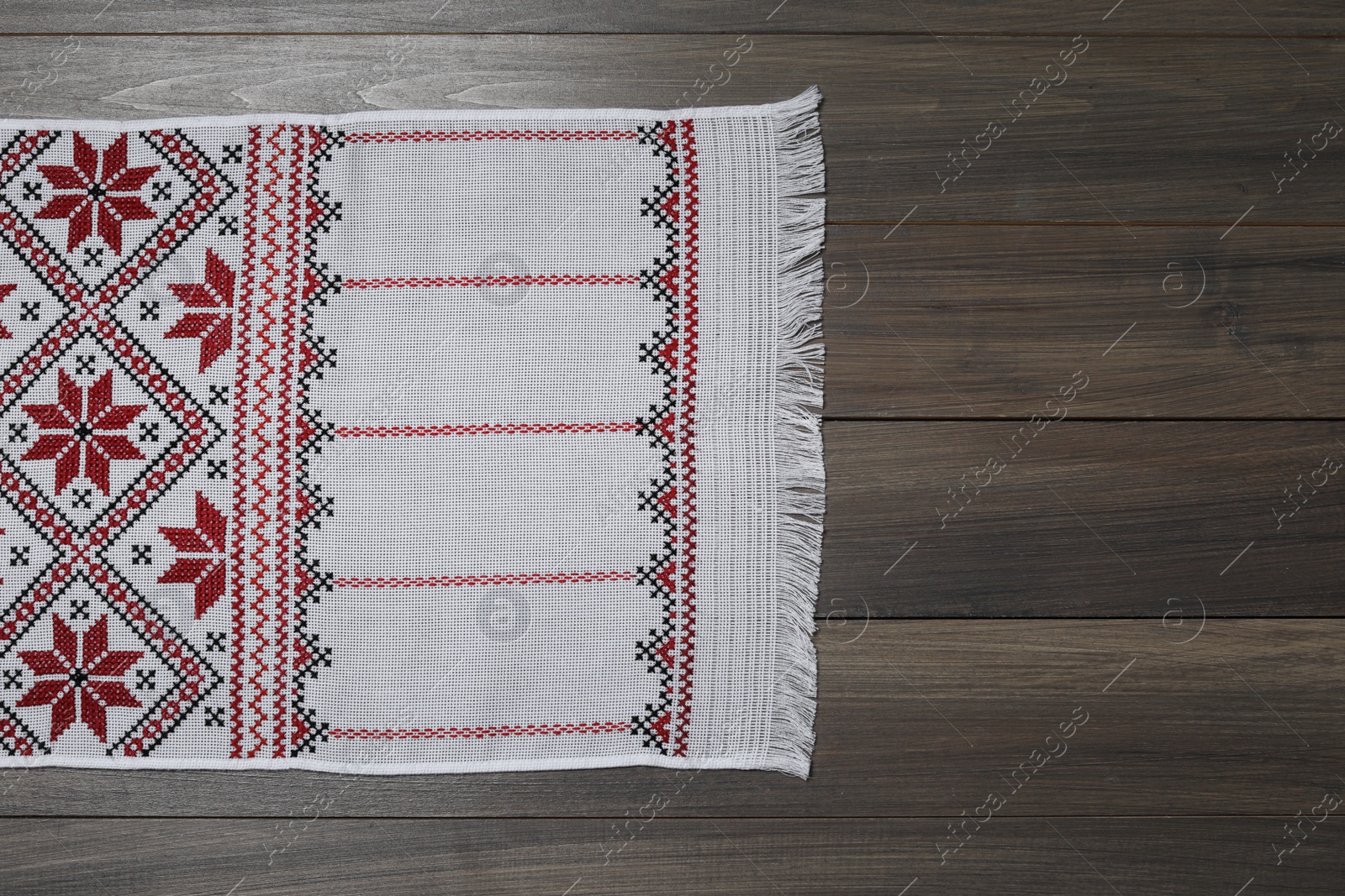 Photo of Beautiful rushnyk on wooden table, top view with space for text. Ukrainian national embroidery