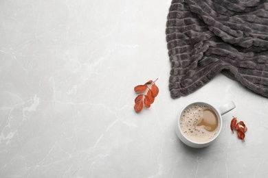 Flat lay composition with coffee and warm plaid on light marble table, space for text