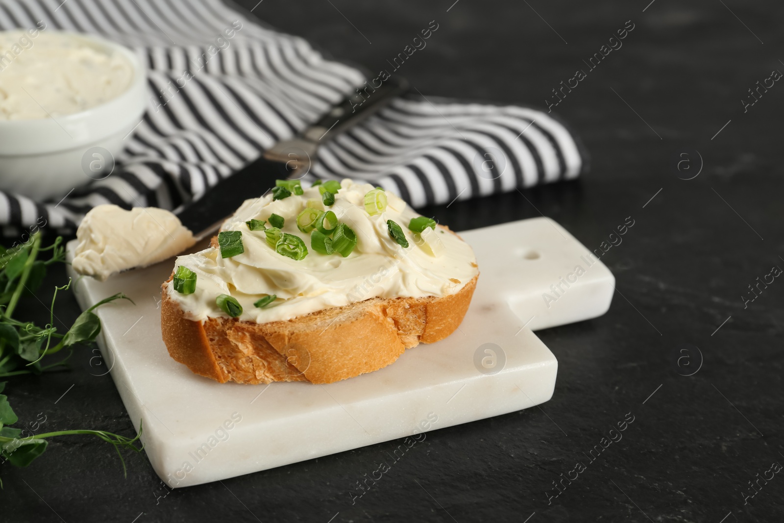 Photo of Delicious sandwich with cream cheese and microgreens on black table