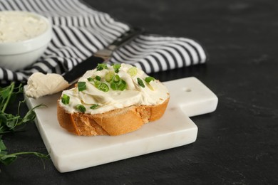 Photo of Delicious sandwich with cream cheese and microgreens on black table