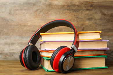 Photo of Books and modern headphones on wooden table