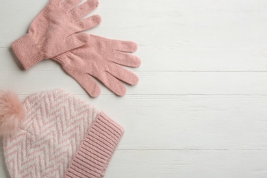 Woolen gloves and hat on white wooden background, flat lay. Space for text