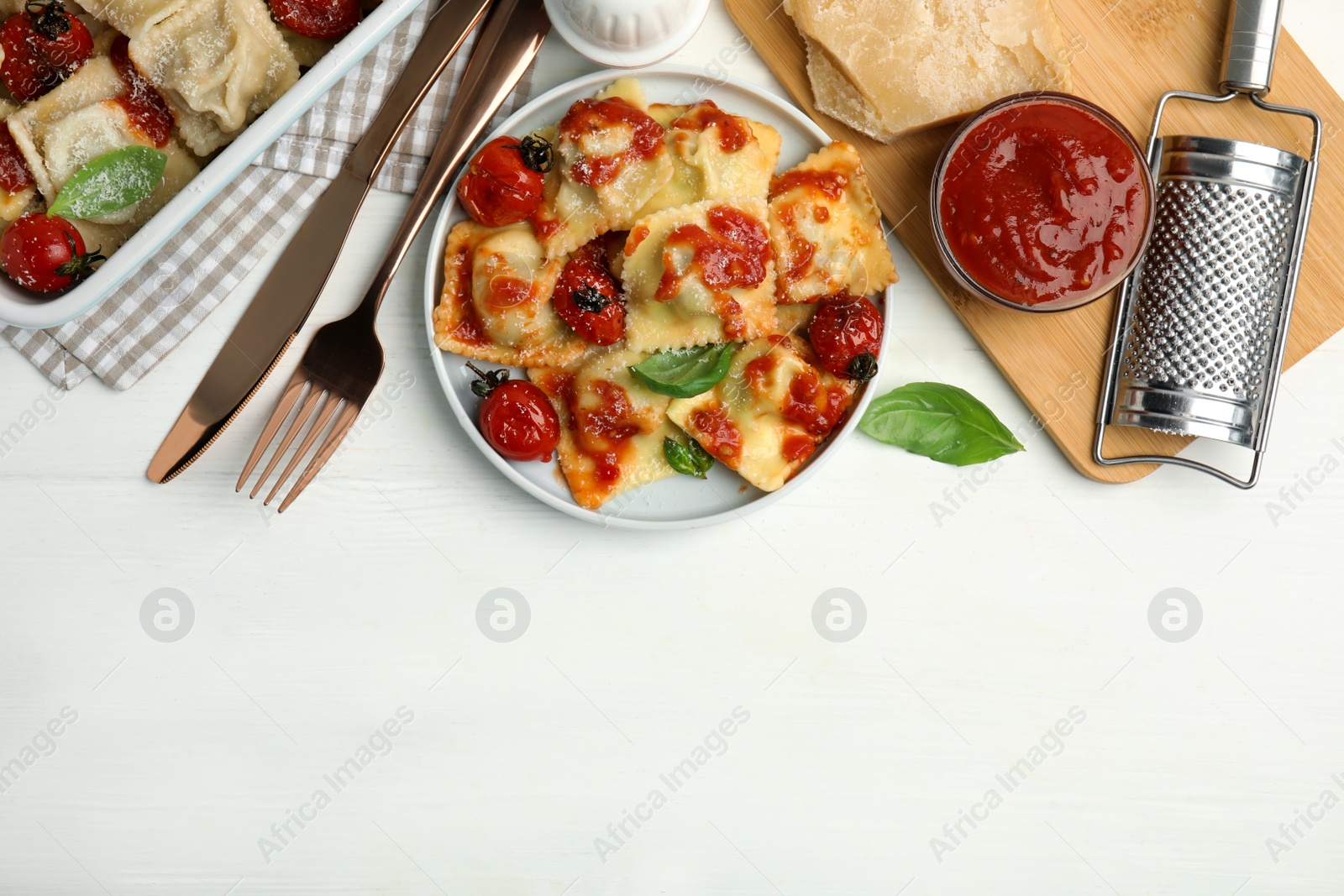 Photo of Tasty ravioli with tomato sauce served on white wooden table, flat lay. Space for text