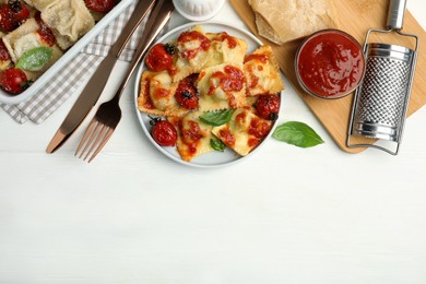 Tasty ravioli with tomato sauce served on white wooden table, flat lay. Space for text