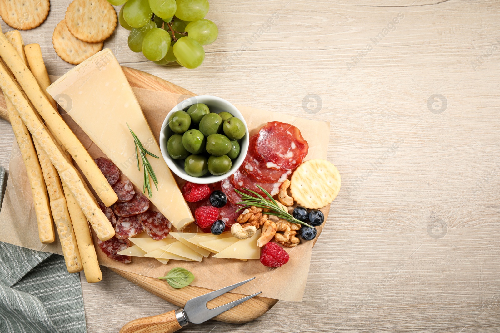 Photo of Snack set with delicious Parmesan cheese on light wooden table, flat lay. Space for text