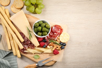 Photo of Snack set with delicious Parmesan cheese on light wooden table, flat lay. Space for text