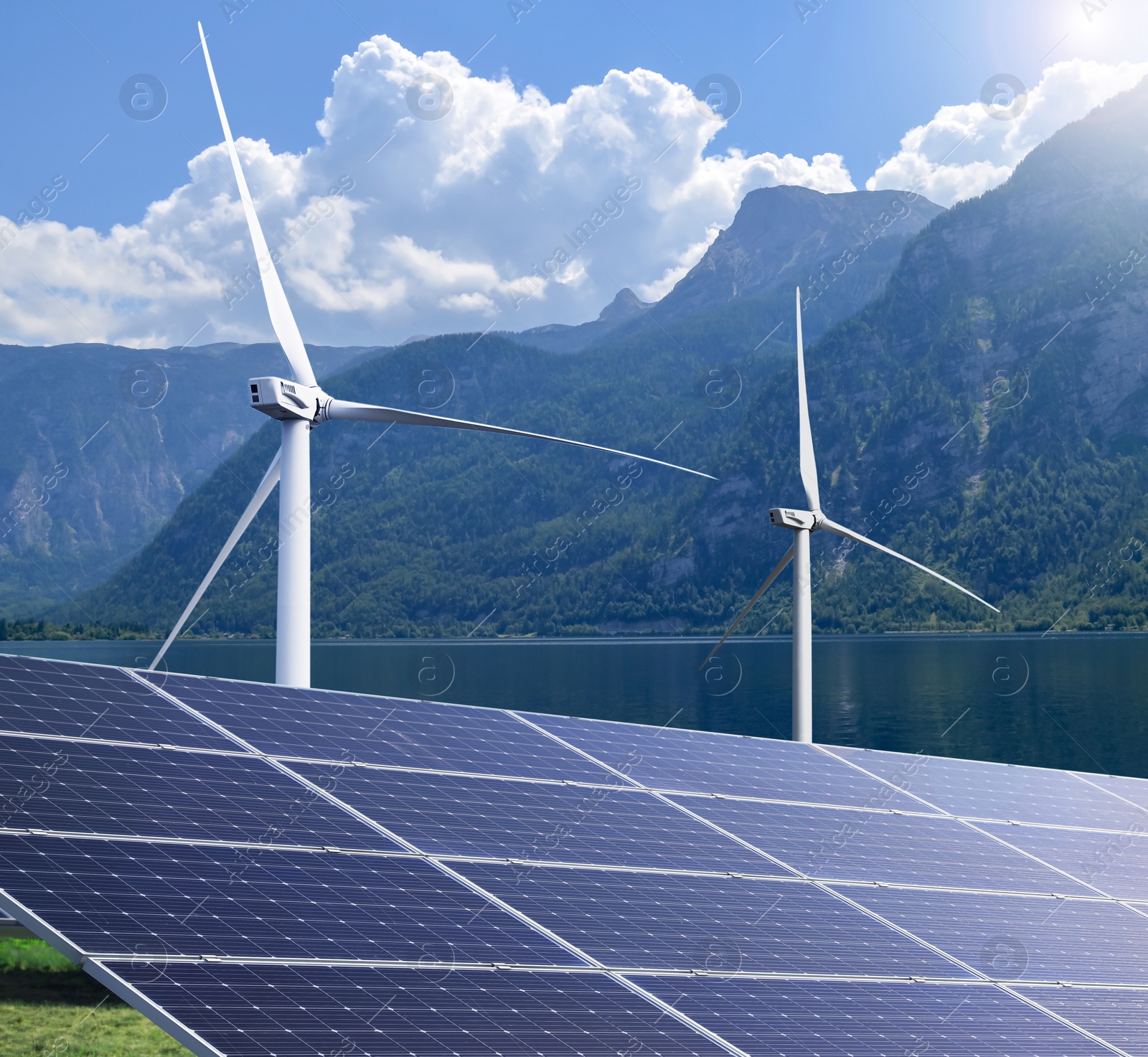 Image of Alternative energy sources. Wind turbines installed in water near bank with solar panels