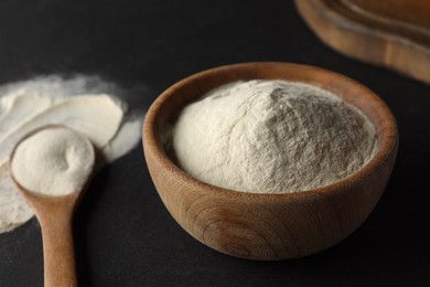 Photo of Bowl and spoon of agar-agar powder on black background, closeup