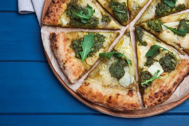 Photo of Delicious pizza with pesto, cheese and arugula on blue wooden table, top view