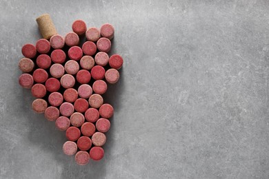 Photo of Grape made of wine bottle corks on grey table, top view. Space for text