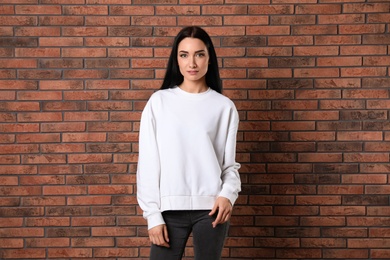 Portrait of young woman in sweater at brick wall. Mock up for design