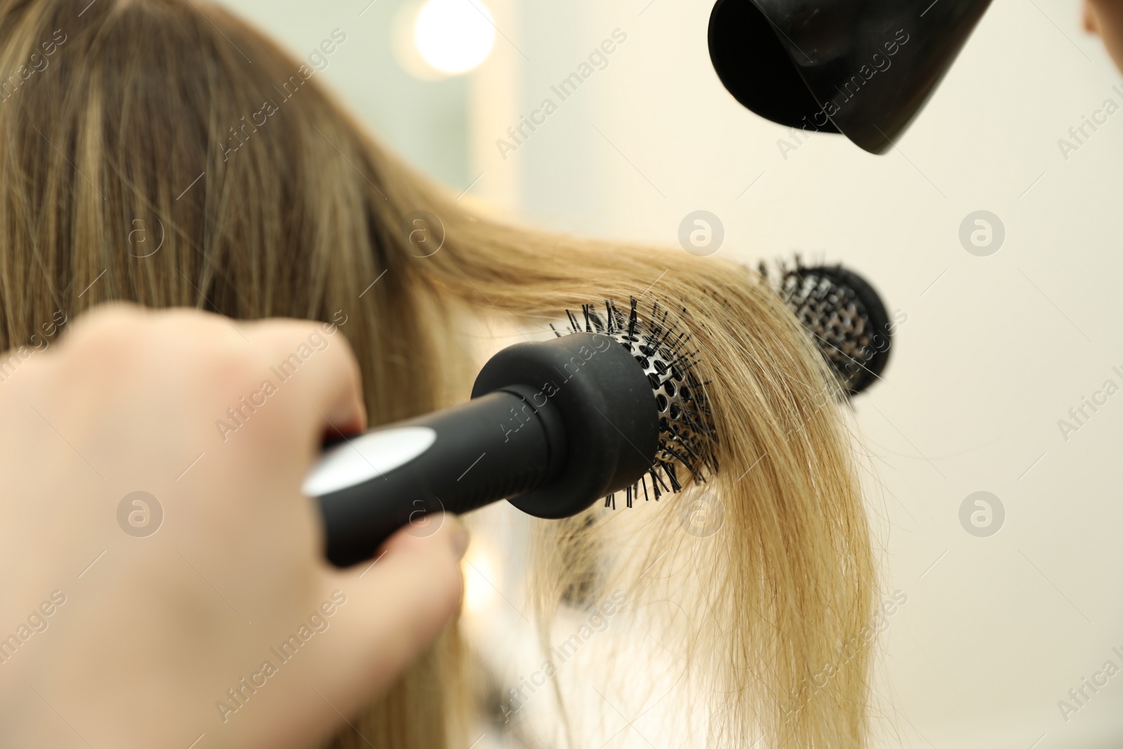 Photo of Stylist drying client's hair in beauty salon, closeup