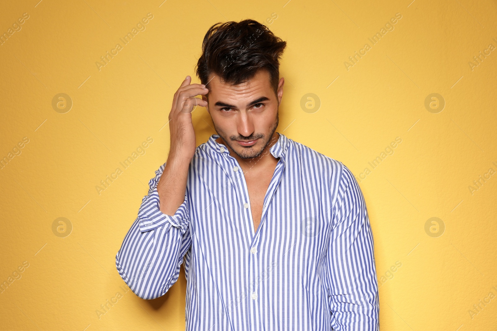 Photo of Young man with trendy hairstyle posing on color background