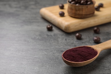 Spoon with acai powder on dark table