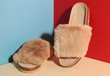 Pair of soft slippers on color background