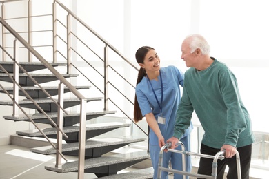 Nurse assisting senior man with walker in hospital