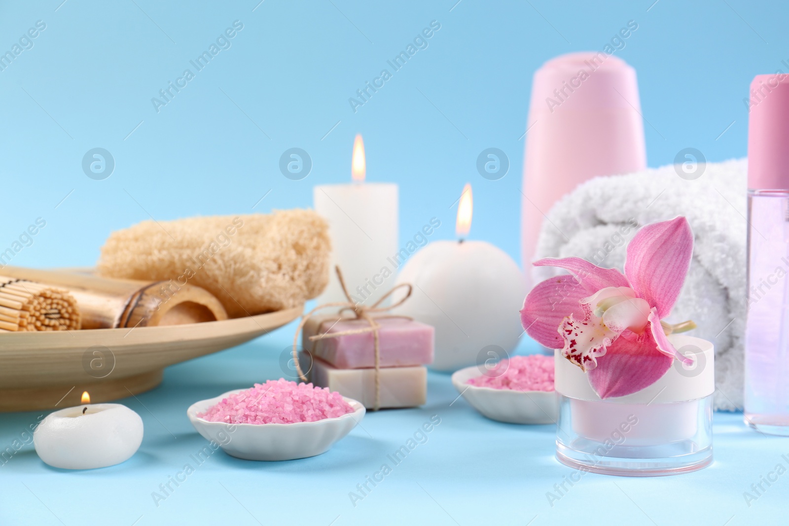 Photo of Retreat concept. Composition with different spa products, burning candles and beautiful orchid on light blue background