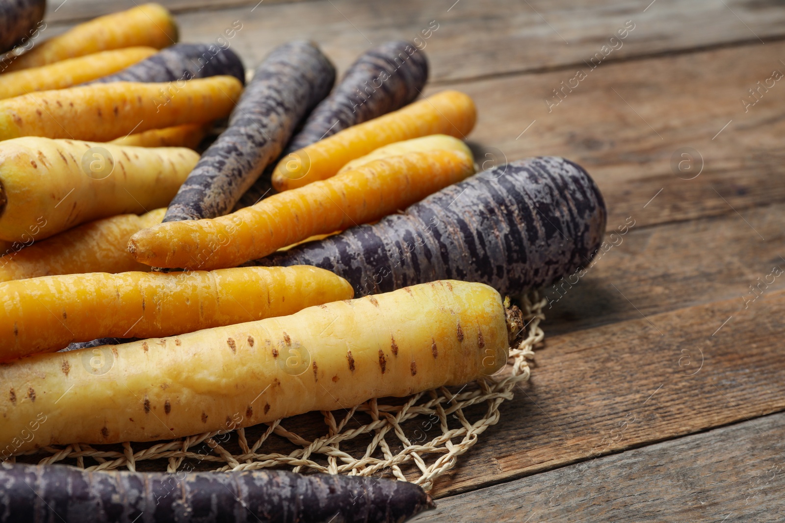 Photo of Many different raw carrots on wooden table, closeup